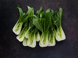 Top down view of a pile of bok choy clusters against a dark background.