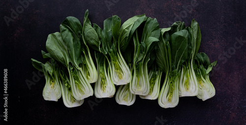 Photography Many bok choy clusters in a row against a dark background.