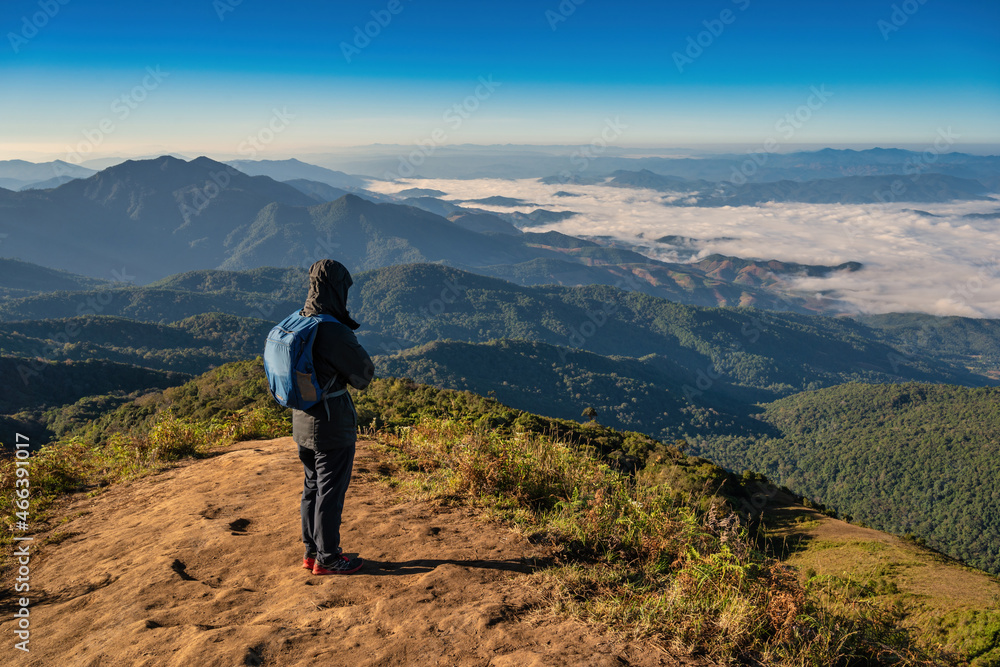 Man hiking looking at mountain range on the top of mountain in tropical forest, Outdoor adventure travel concept