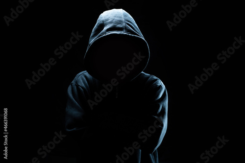 Computer hacker in black mask and hoodie. Obscured dark face. Data thief, internet fraud, cyber security concept. photo