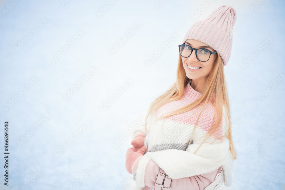 Young woman in glasses and knitted pink hat in winter on background of snow, happy portrait of girl Young woman in glasses and knitted pink hat in winter on background of snow, happy portrait of girl