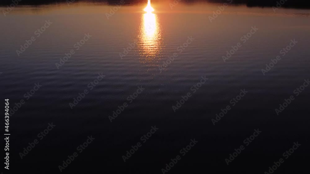 Cinematic aerial shot of stunning orange sunset above lake water Cinematic aerial shot of stunning orange sunset above lake water