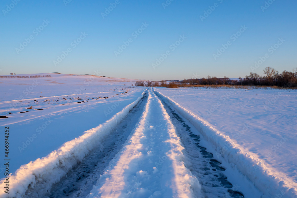 Winter road. Road track in deep snow. Winter evening landscape.