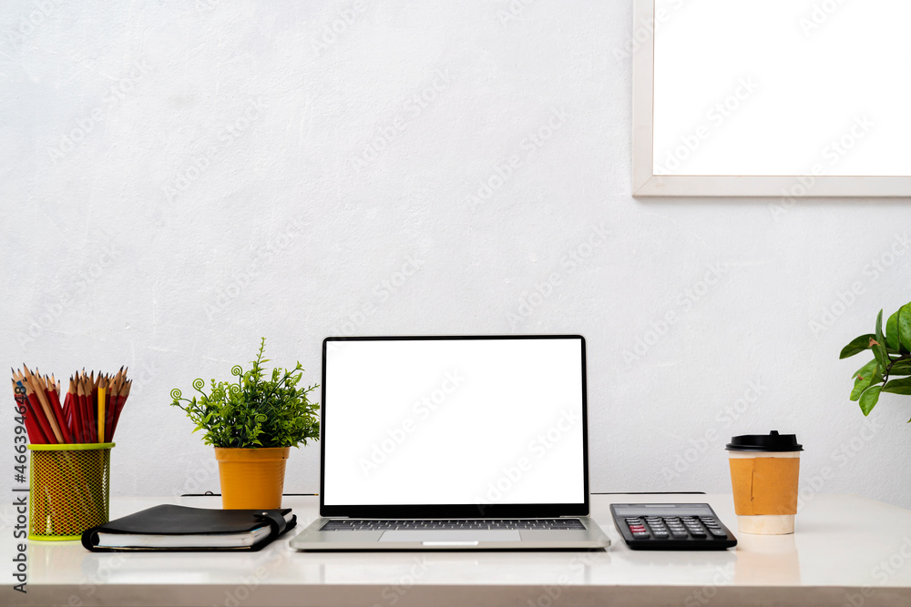 Fototapeta premium Laptop computer with blank screen, home plant, watering can, unrecognizable picture in frame on dresser.