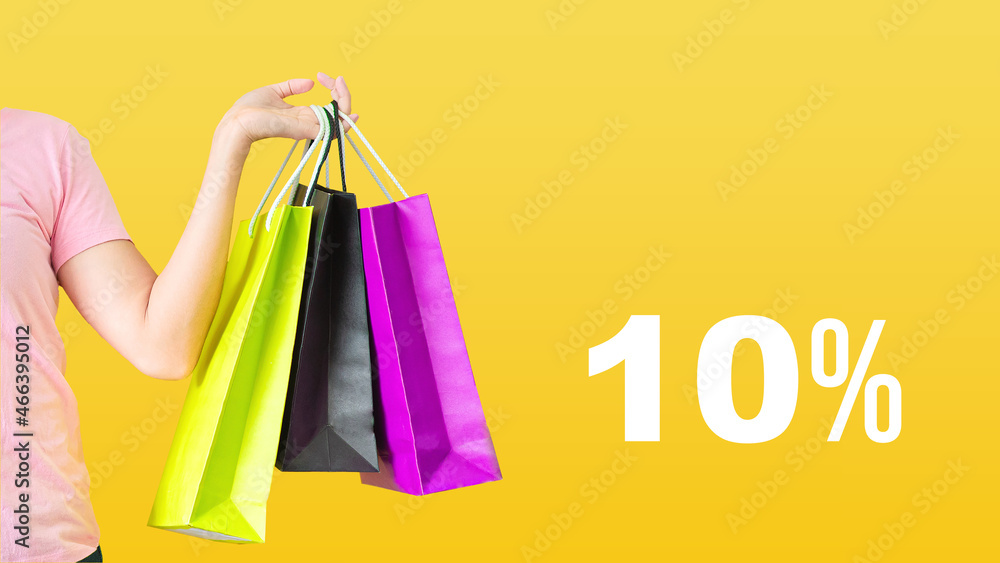 10% discount.Sale with female hands holding shopping bags on yellow background. Black Friday and sale concept.