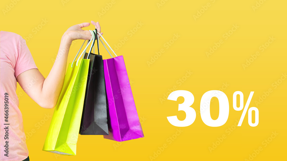 30% discount.Sale with female hands holding shopping bags on yellow background. Black Friday and sale concept.