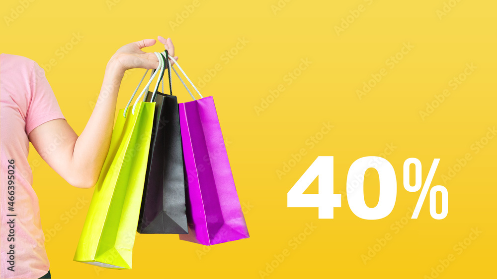 40% discount.Sale with female hands holding shopping bags on yellow background. Black Friday and sale concept.