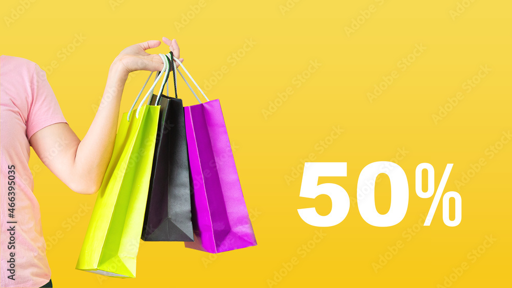 50% discount.Sale with female hands holding shopping bags on yellow background. Black Friday and sale concept.