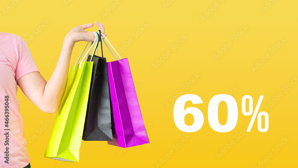 60% discount.Sale with female hands holding shopping bags on yellow background. Black Friday and sale concept.
