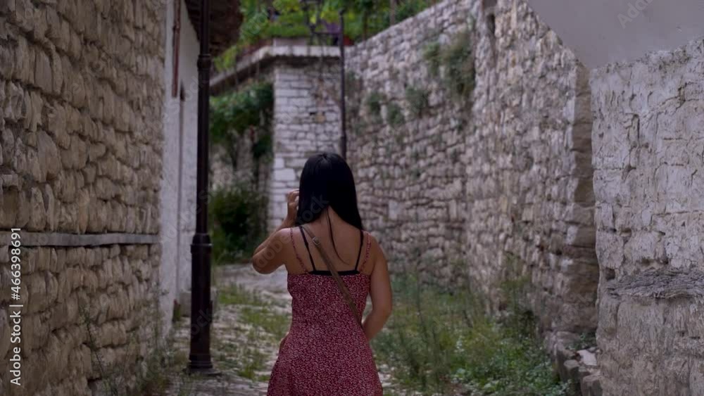 Young female tourist walking through Mediterranean stone village Young female tourist walking through Mediterranean stone village