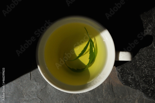 Top view hot hemp tea with cannabis leaf in a white cup
