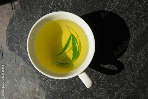 Top view hot hemp tea with cannabis leaf in a white cup
