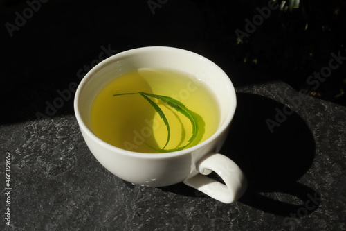 Top view hot hemp tea with cannabis leaf in a white cup
