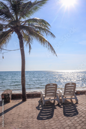 white chairs were placed on the beach on a clear day with beautiful waters