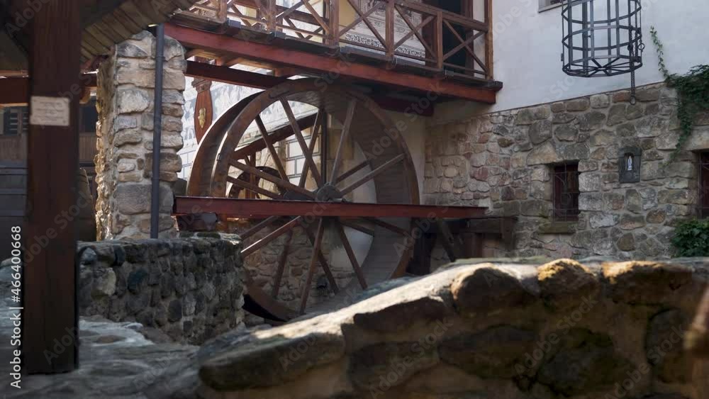 Old wooden watermill wheel in a castle courtyard in sunlight,Czechia. Old wooden watermill wheel in a castle courtyard in sunlight,Czechia.