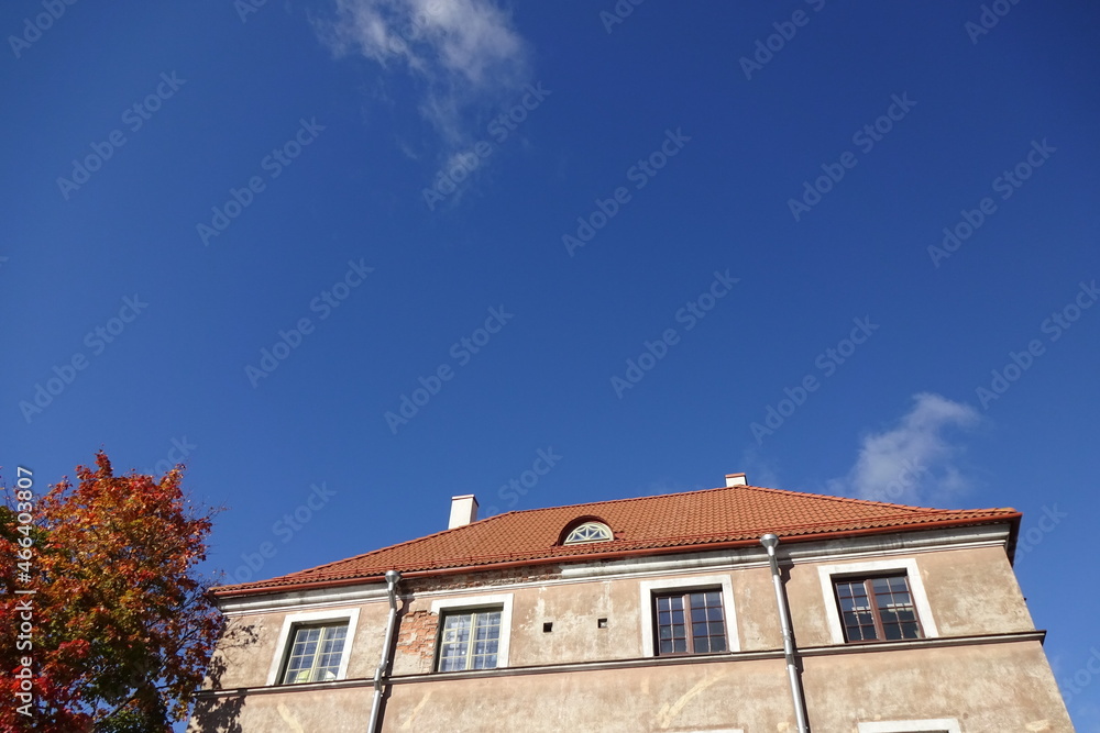 Close up of a house with red tiled roof. Cear blue sky background. Golden autumn tree foliage on the left. Autumn mood. Pelgulinna, Tallinn, Estonia, Europe. September 2021 Close up of a house with red tiled roof. Cear blue sky background. Golden autumn tree foliage on the left. Autumn mood. Pelgulinna, Tallinn, Estonia, Europe. September 2021
