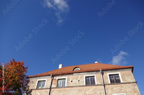 Close up of a house with red tiled roof. Cear blue sky background. Golden autumn tree foliage on the left. Autumn mood. Pelgulinna, Tallinn, Estonia, Europe. September 2021 © JSF15photo