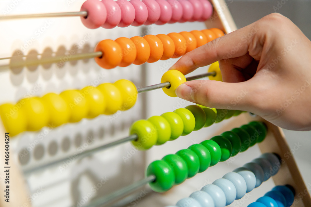 Male hand calculating with beads on wooden rainbow abacus for number calculation. Mathematics learning concept Male hand calculating with beads on wooden rainbow abacus for number calculation. Mathematics learning concept