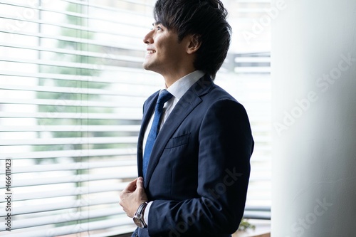 窓を見つめる若い日本人ビジネスマン