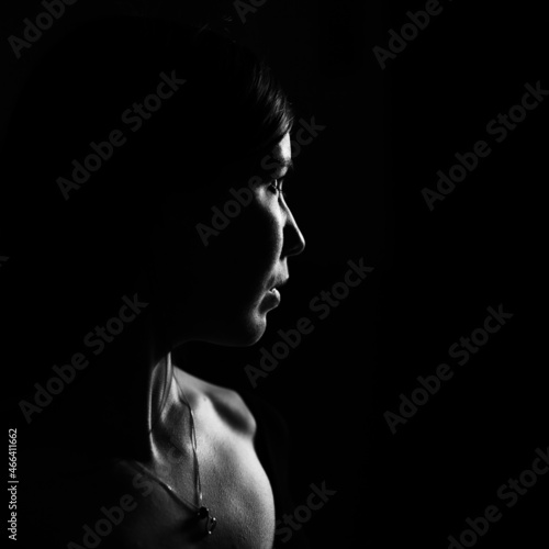 Portrait of a young woman in profile with dramatic light. Black and white photo.