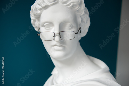 Plaster statue head with glasses. Antiquity and modernity. Myopia and hyperopia treatment concept