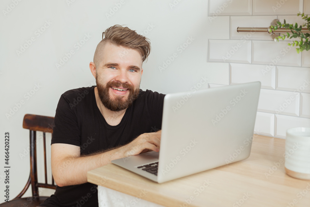 Happy smiling young man watching and working on computer laptop at home. Technologies, remote work and social networks Happy smiling young man watching and working on computer laptop at home. Technologies, remote work and social networks