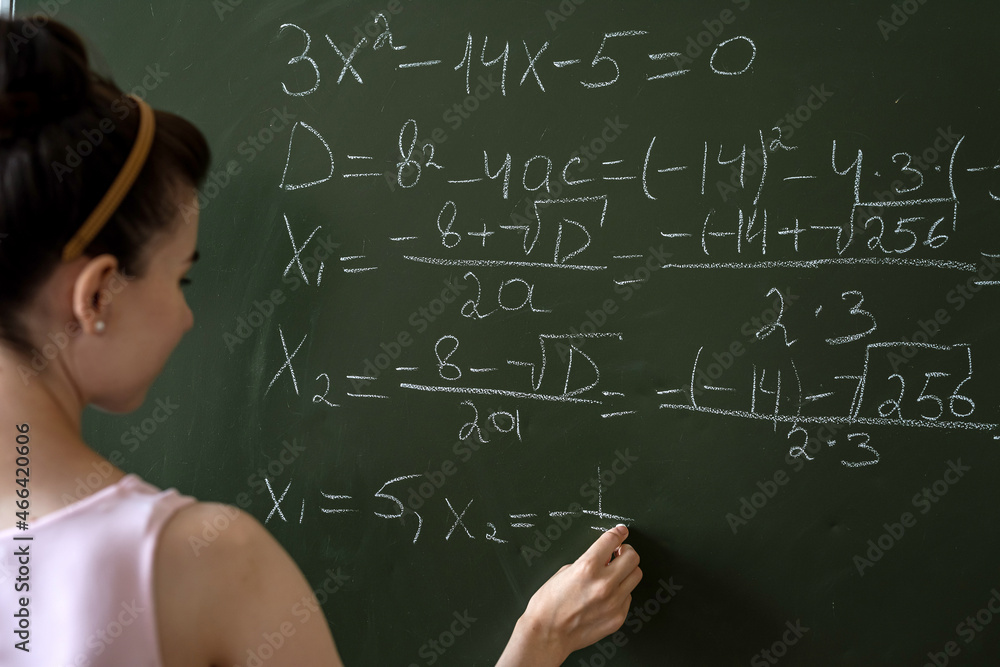 Clever female student writing on a chalkboard completing mathematical formulas Clever female student writing on a chalkboard completing mathematical formulas