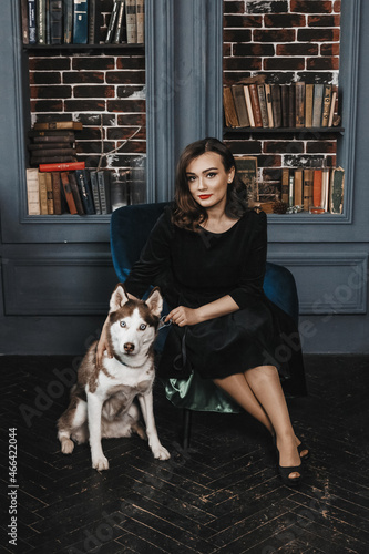 Woman is sitting with her husky near bookshelfs. © Irene Bondarchuk