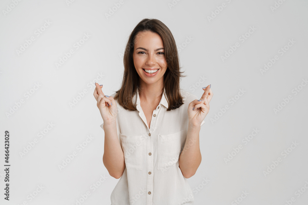 Young european woman smiling while holding fingers crossed for good luck Young european woman smiling while holding fingers crossed for good luck