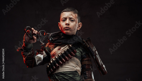 Armoured preschool boy with gun on his shoulder in dark background