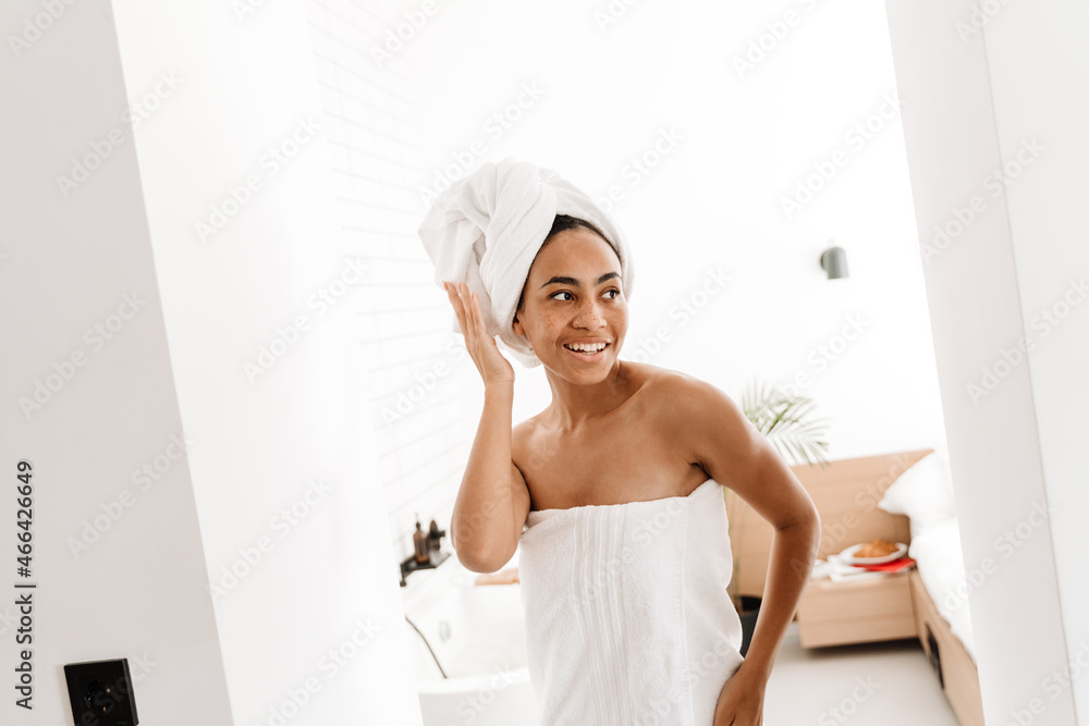 Black woman wrapped in towels smiling while posing at home Black woman wrapped in towels smiling while posing at home