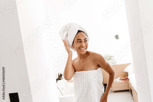 Black woman wrapped in towels smiling while posing at home