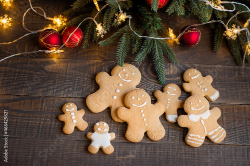 Gingerbread family on the background of Christmas attributes (Christmas tree, balloons, glowing garland).