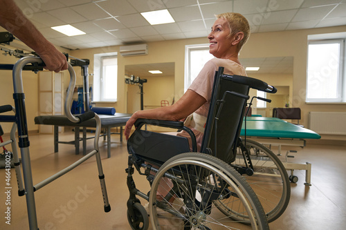 Physiotherapist assisting female patient in using walker at clinic