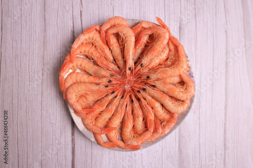 Portion of cooked white prawns from Huelva on gray light wooden background