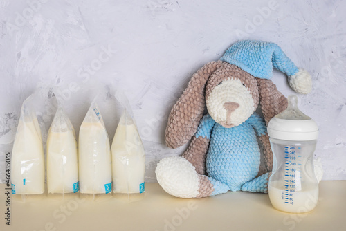 Bags with breast milk with knitted toy. Breast pump on yellow background. Milk bank. Expressing breast milk. Breast-feeding. Freezing and storing milk. Donated. Copyspace