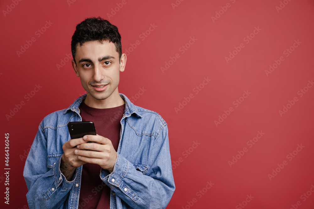 Young middle eastern man smiling and using mobile phone Young middle eastern man smiling and using mobile phone
