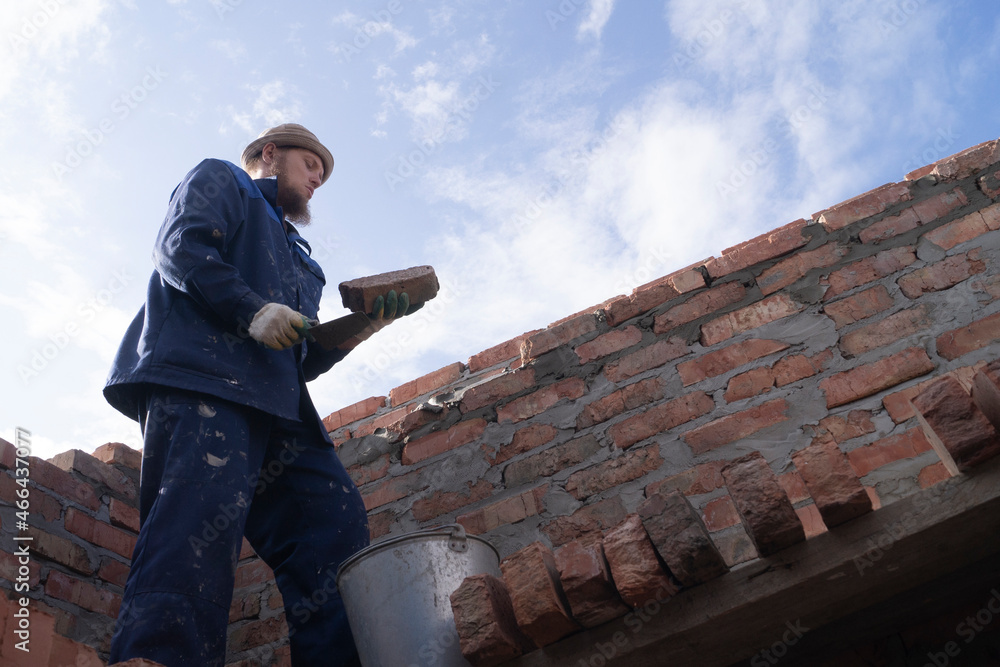Fototapeta premium bricklayer lays bricks on scaffolding