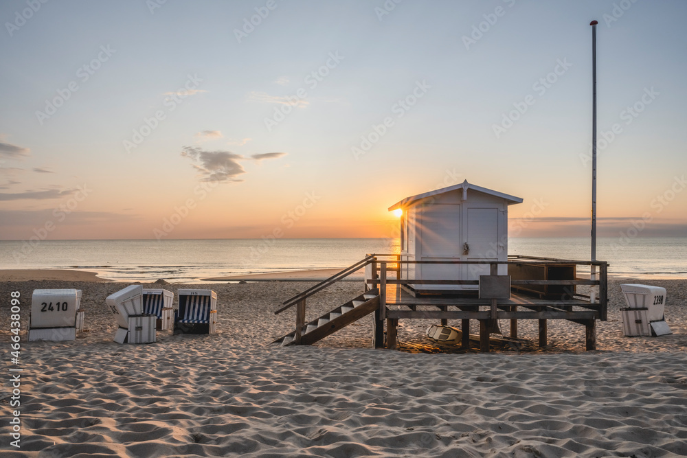 Lifeguard hut and hooded beach chairs at sandy coastal beach during sunset Lifeguard hut and hooded beach chairs at sandy coastal beach during sunset