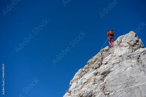 Male mountaineer climbing on Alpi Apuane hill with rope in front of clear sky photo