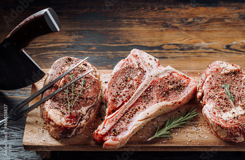 Obraz na płótnie three lovely raw marbled black Angus beef steaks flavored with a mixture of ground pepper and ready to cook and serve on a dark wooden background. w salonie