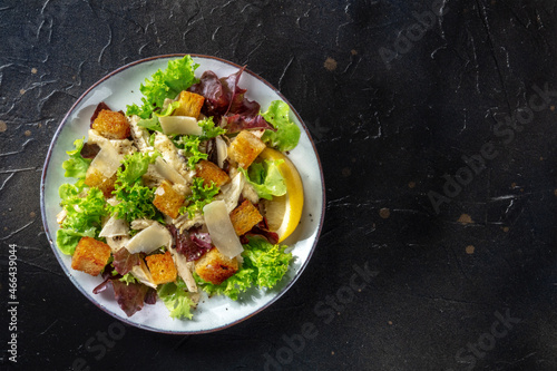 Chicken Caesar salad, overhead shot on a black background with a place for text