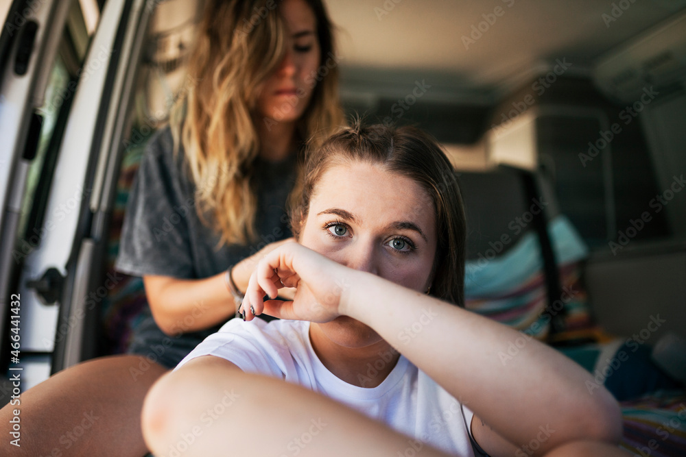 Young woman doing haire of female friend in motor home Young woman doing haire of female friend in motor home