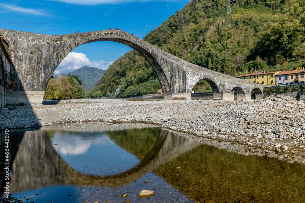 Fototapeta premium The famous ancient Ponte della Maddalena or del Diavolo is reflected in a puddle of water, Lucca, Italy