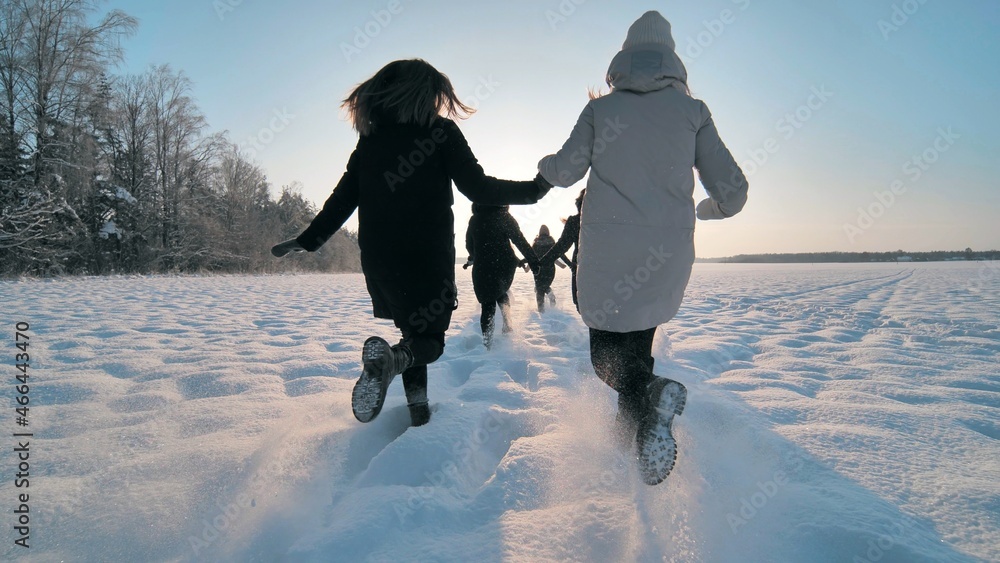 Cheerful girls run across the snow-covered field. - obrazy, fototapety, plakaty 