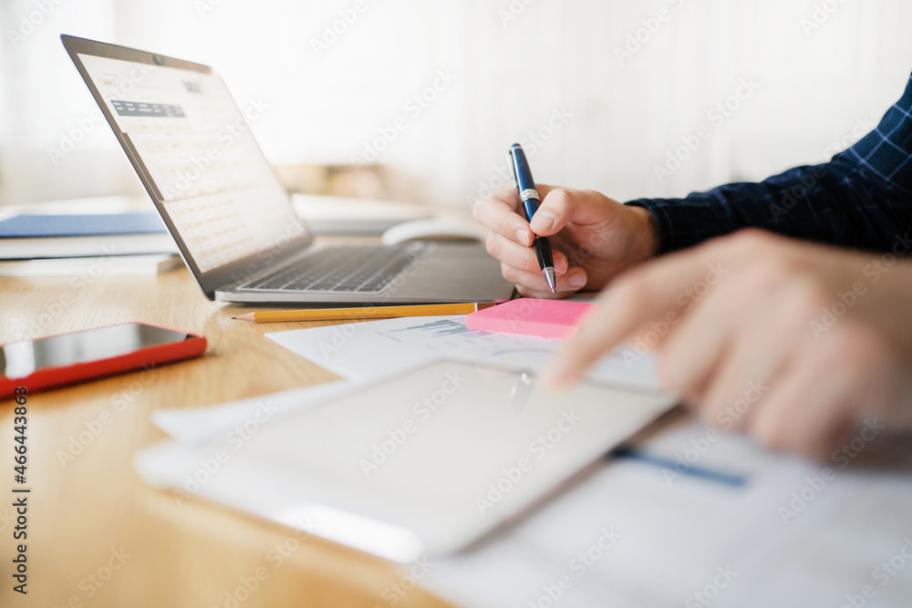 Workplace in the office. The laptop is open on the table. Online business expenses for advertising. A man works on the Internet with papers counts finances. Workplace in the office. The laptop is open on the table. Online business expenses for advertising. A man works on the Internet with papers counts finances.