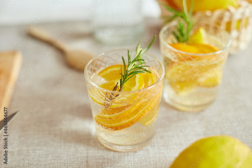 Citrus and rosemary fresh lemonade in glass on a white table at home, summer drink, detox healthy water. Citrus and rosemary fresh lemonade in glass on a white table at home, summer drink, detox healthy water.