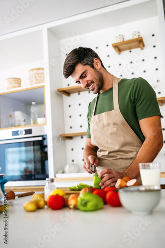 Cheerful young man preparing healthy food in the kitchen