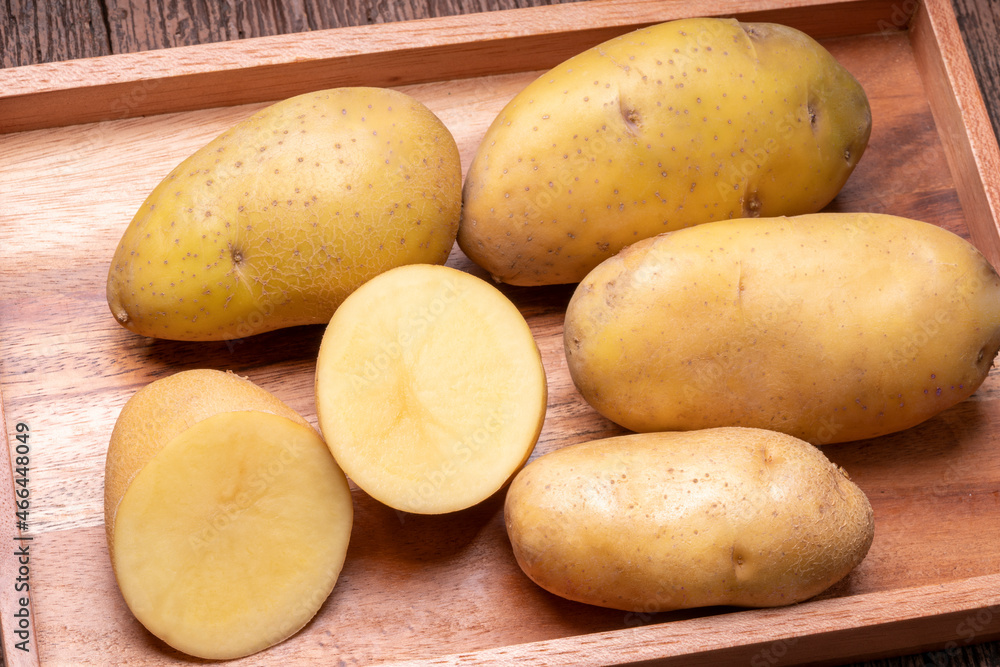 Fresh potatoes and sliced in wooden plate, Table top view Raw potato on a wooden table background.