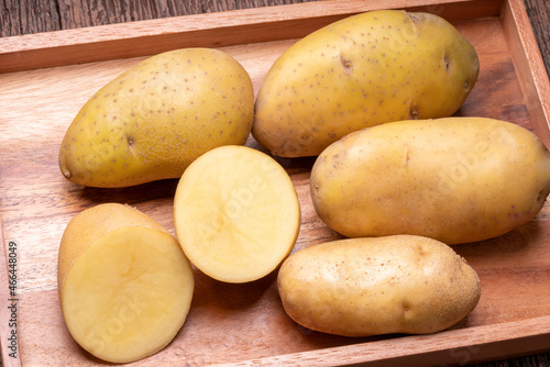 Fresh potatoes and sliced in wooden plate  Table top view Raw potato on a wooden table background.